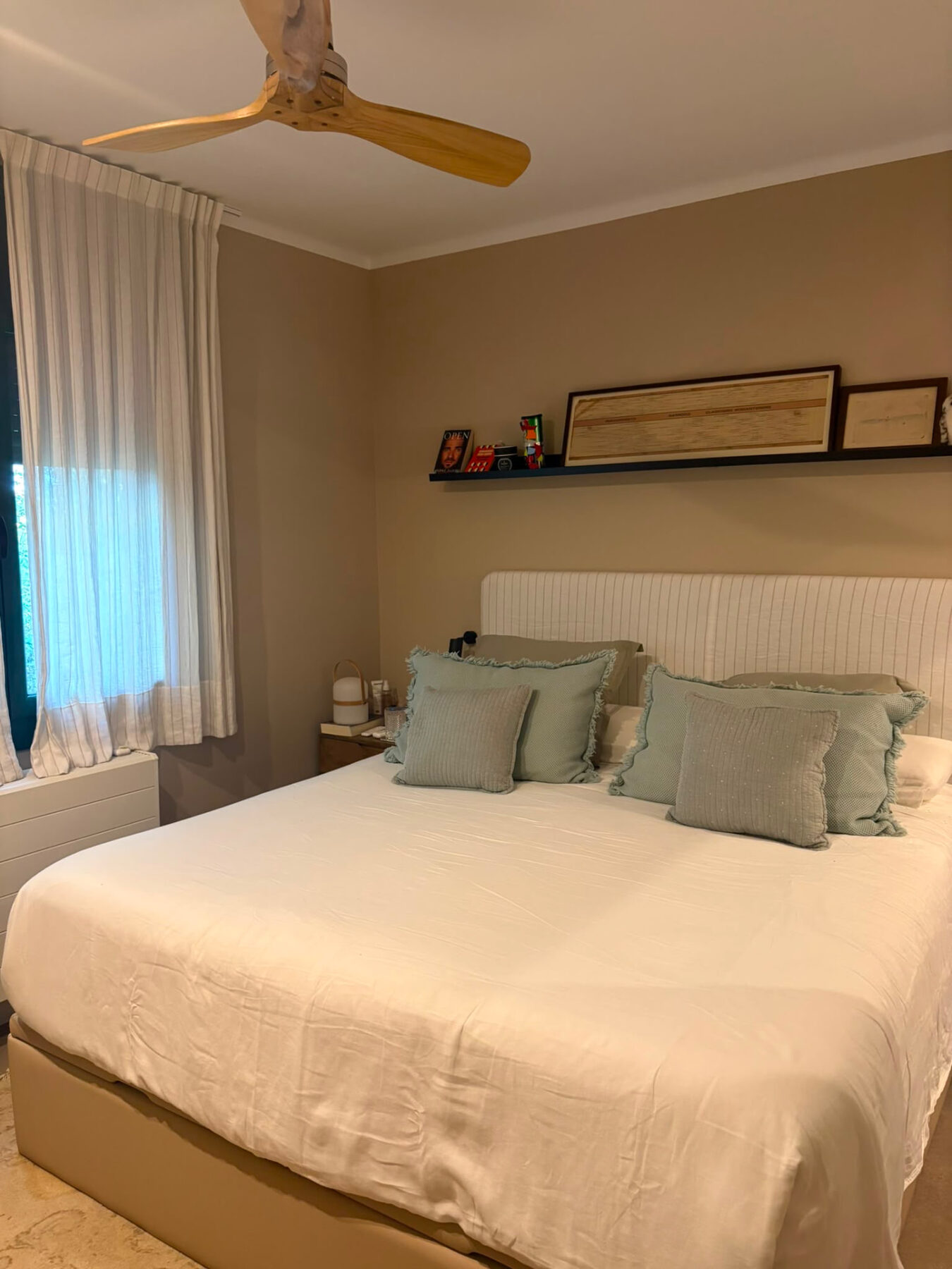 Main bedroom with a wooden ceiling fan, striped curtains and light blue cushions on a white bed — Mediterranean Home on the Costa Brava