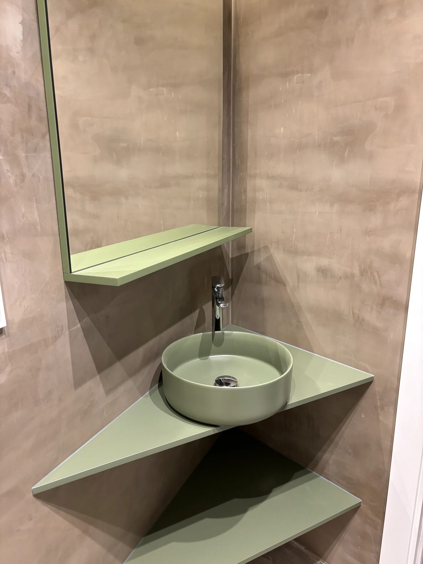 Corner basin in soft green against textured taupe walls with a matching green shelf — City Apartment in Barcelona, bathroom with bespoke basin