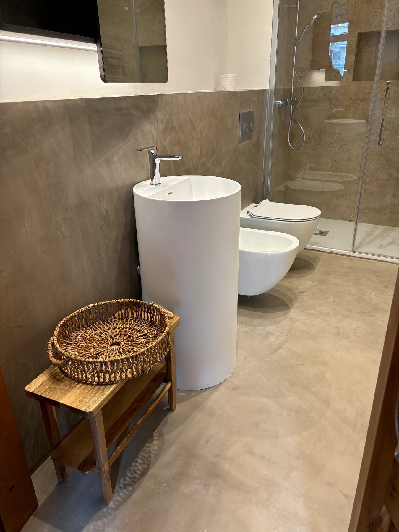 Bathroom finished in microcement with a white basin and a walk-in shower — City Apartment in Barcelona