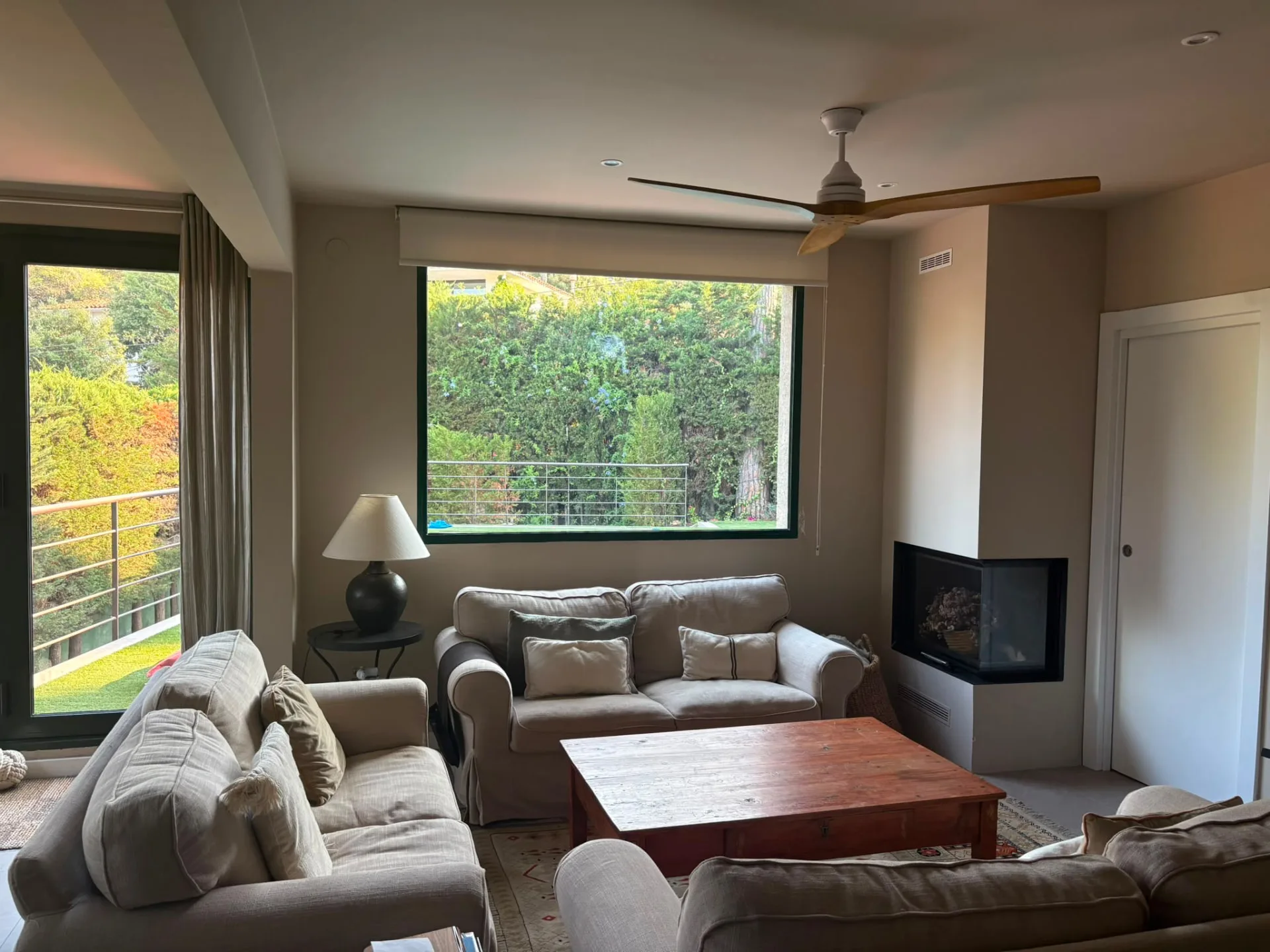 Family living room with linen sofas, a corner fireplace and a large window onto the garden — Mediterranean Home on the Costa Brava