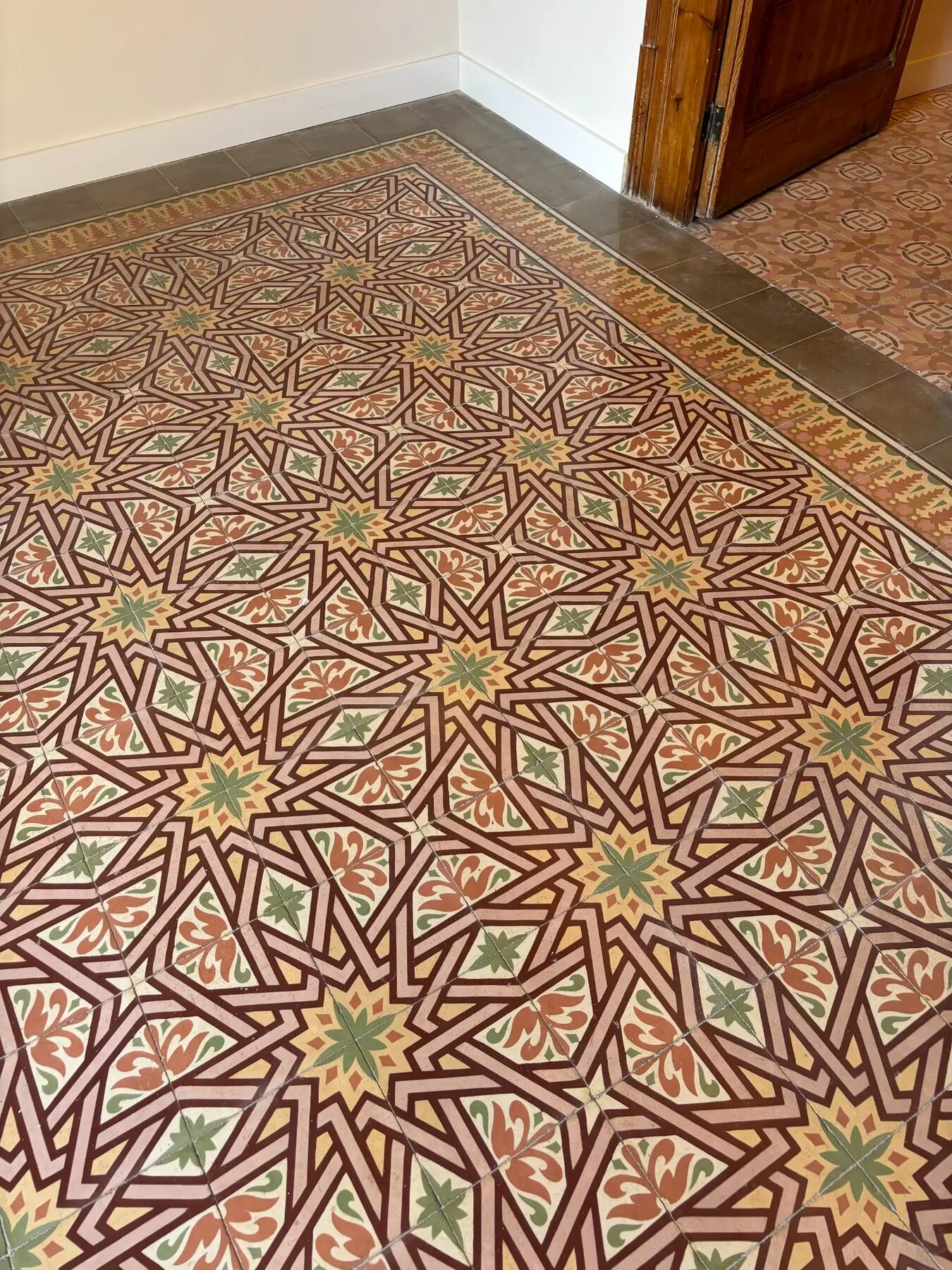 Original hydraulic floor tiles with a red, green and cream pattern — City Apartment in Barcelona