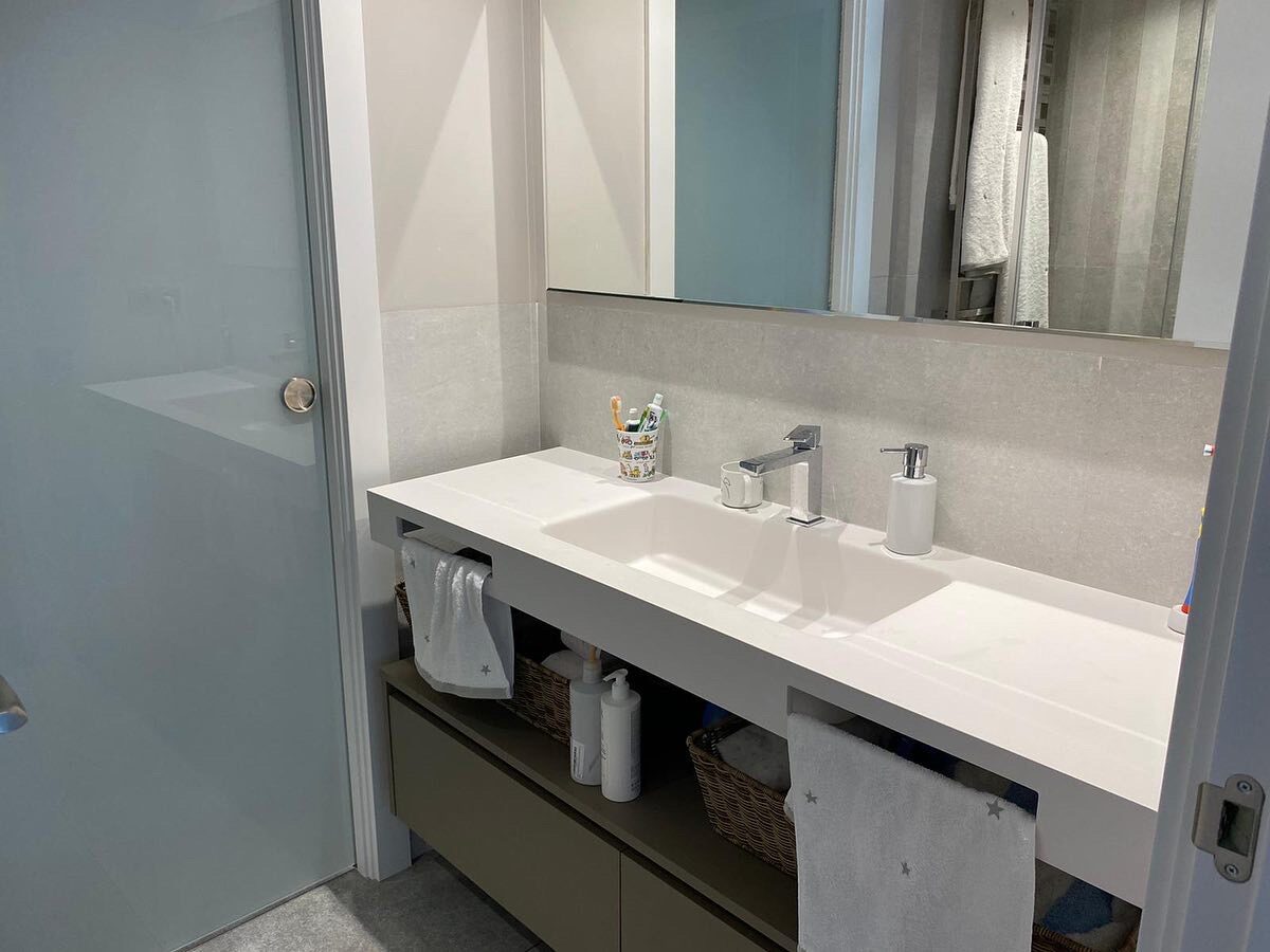 Children’s bathroom with a long white vanity unit, two basins, a large mirror and light grey tiling — Family Home in Barcelona’s Upper Districts