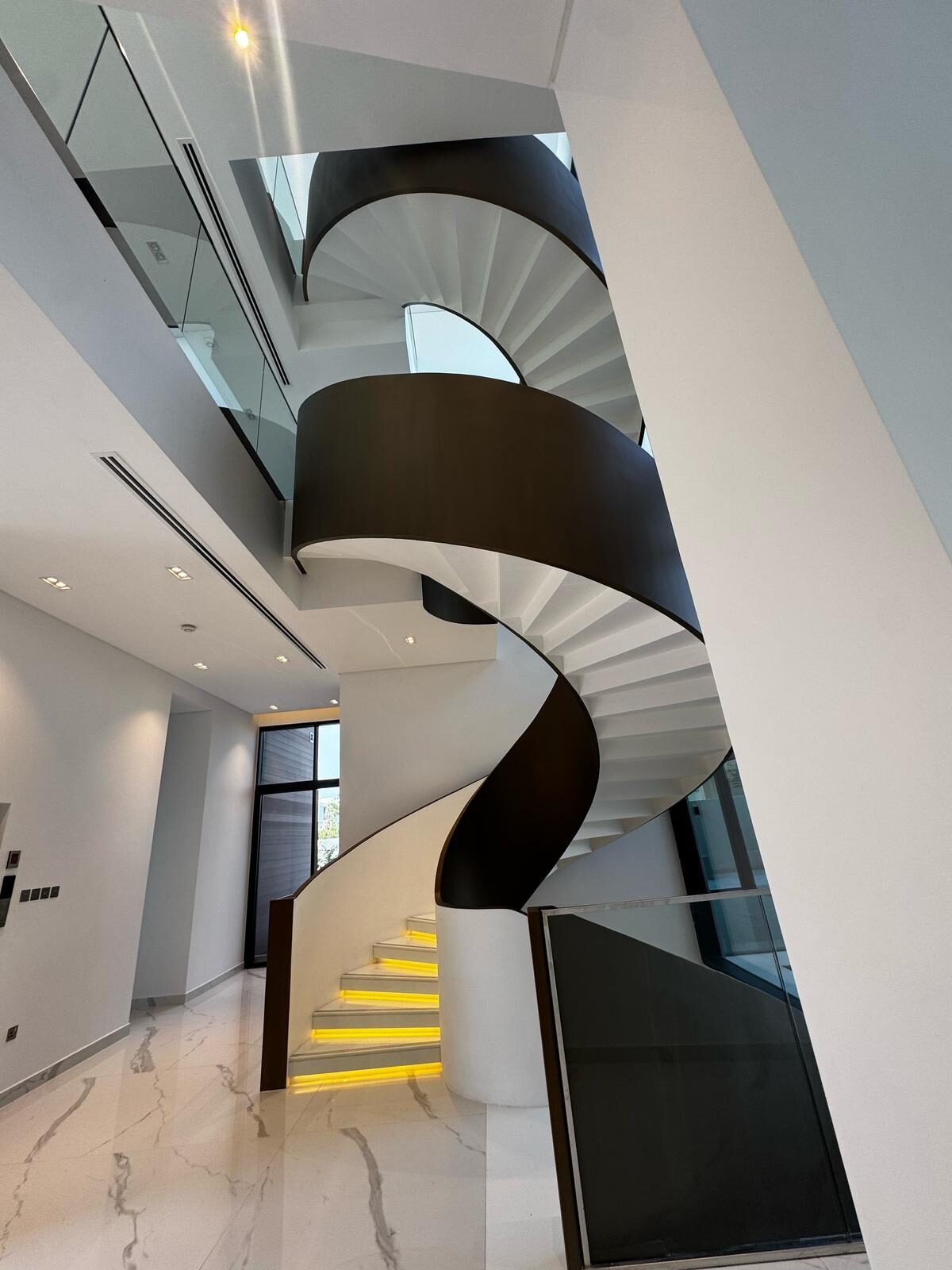Vertical view of the spiral staircase curve with integrated lighting in the treads — Contemporary International Villa