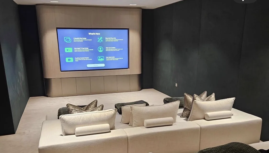 Home cinema with upholstered dark green walls, tiered seating and a large screen — Contemporary International Villa