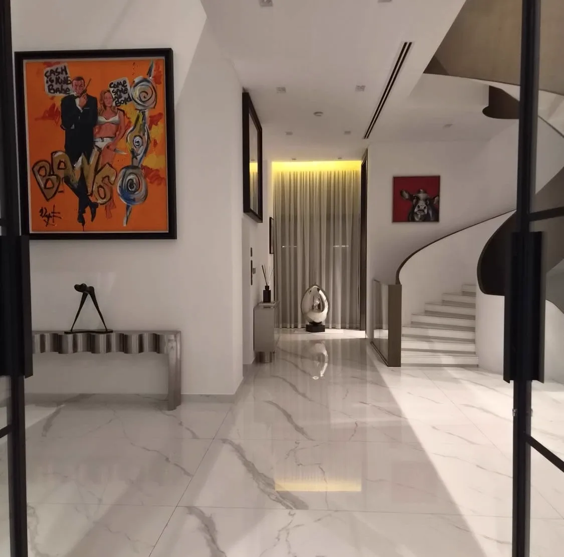 Entrance hall with marble floors, contemporary artwork and the sculptural spiral staircase — Contemporary International Villa